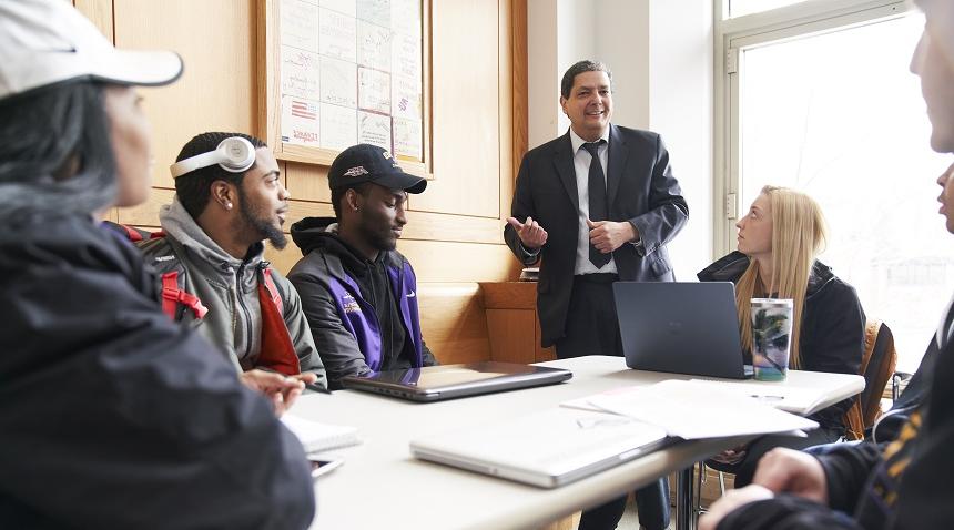 students and a faculty member around a table smiling